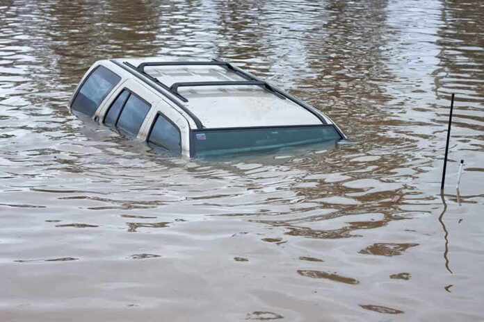 A partially submerged vehicle in floodwaters