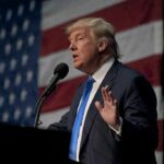 Trump SLASHES Drug Costs — Massive Savings A man in a suit speaking at a podium with an American flag in the background