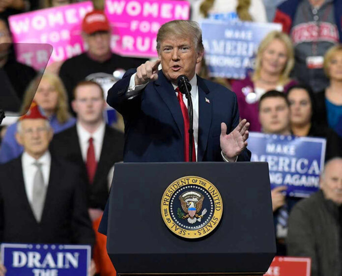 Person speaking at rally with crowd behind podium