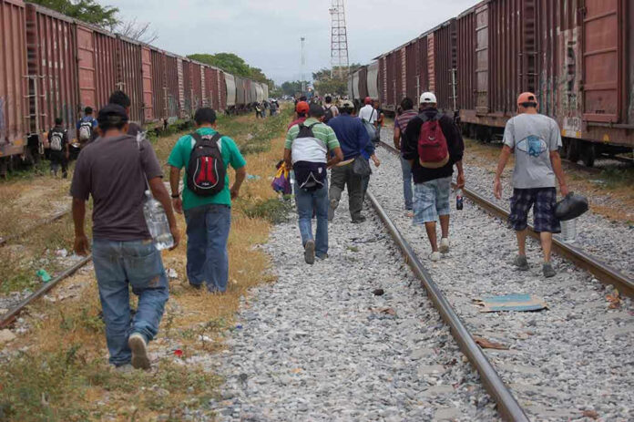 People walking along train tracks carrying backpacks