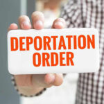 Hand holding sign with Deportation Order text.
