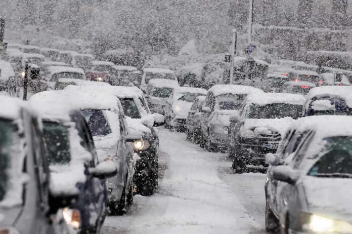 Traffic jam with cars covered in heavy snow during a snowstorm