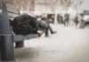 Person sleeping on a bench in a public area.