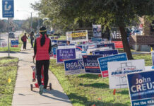 NEW Trump Hating CANDIDATE Jumps in the RING Person walking with stroller past numerous election campaign signs.