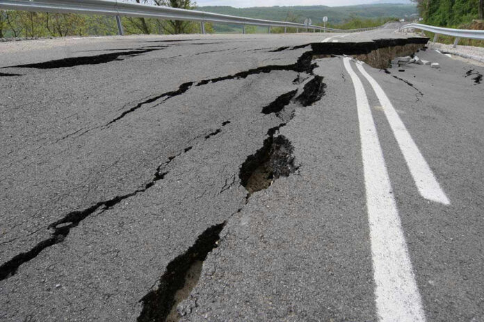 1044748162 Road damaged by significant cracks and fissures.