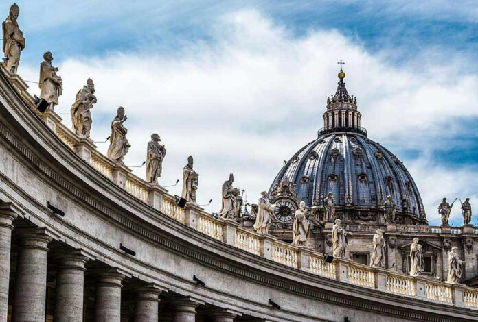 368201633 St. Peters Basilica dome with statues and clouds.