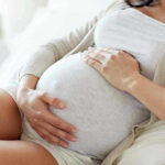 Vatican Calls for Immediate Ban on Surrogacy Pregnant woman holding her belly, sitting comfortably.