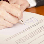 Massive TRADE AGREEMENT–20 Years of NEGOTIATIONS! Hand signing a document with a pen.