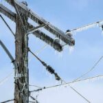 Winter Storm CRIPPLES Power Grid–See WHERE Icy power lines and a utility pole against a blue sky