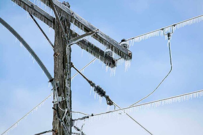 shutterstock_175418288.jpg Icy power lines and a utility pole against a blue sky