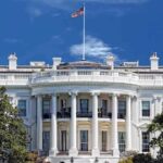 White House THREATENS Major Network Lawsuit The White House with the American flag flying against a blue sky