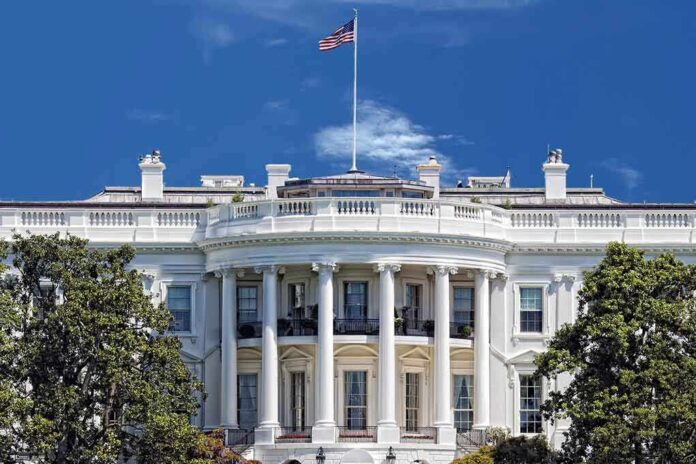 The White House with the American flag flying against a blue sky