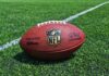 An NFL football resting on a green grass field