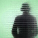 Silhouette behind frosted, textured glass in green light.