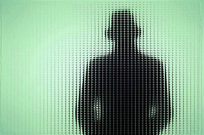 Silhouette behind frosted, textured glass in green light.