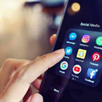 Finger tapping smartphone social media app icons.
