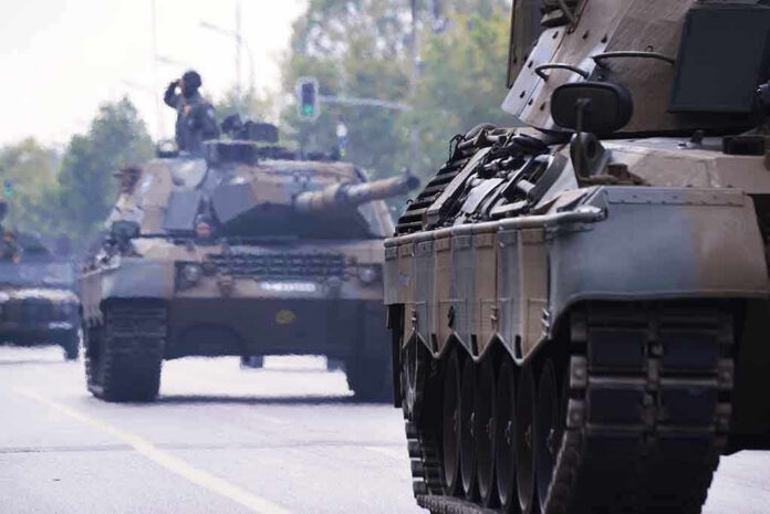 Tanks on a road with soldiers inside.