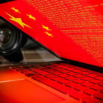CCP Espionage Ring BUSTED—Olympic Family Attacked Laptop screen displaying Chinese flag and code.