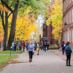 3rd Deadly Dorm Shooting TERRIFIES Community People walking on a college campus in autumn.