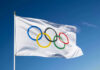 40-Year-Old DESTROYS Age Myth — Celebration Goes Viral Olympic flag waving against clear blue sky.