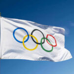 40-Year-Old DESTROYS Age Myth — Celebration Goes Viral Olympic flag waving against clear blue sky.