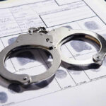 Handcuffs on fingerprint form with fingerprints visible.