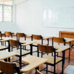 7,000-Teacher Scramble Looms Over NYC Empty classroom with desks, chairs, and whiteboard.
