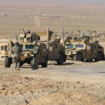 MIDDLE EAST Exit SHOCKS Pentagon — Troops Coming Home Soldiers beside military vehicles in a desert area.