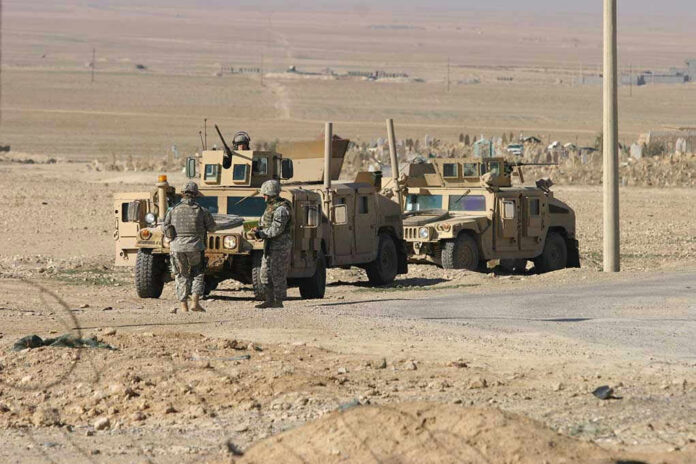 76580419 Soldiers beside military vehicles in a desert area.