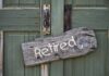 Weathered wooden sign reading Retired hanging on a green door
