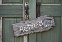 Weathered wooden sign reading Retired hanging on a green door
