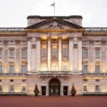 Lodge RAID — ROYAL Tossed Out Front view of Buckingham Palace with illuminated facade and British flag