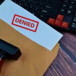 A 'DENIED' stamp on a rejection notice placed on a desk