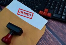 A 'DENIED' stamp on a rejection notice placed on a desk