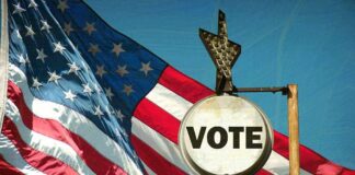 A vintage Vote sign in front of an American flag