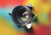 Camera lens protruding through a colorful background