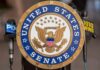 Official seal of the United States Senate with microphones in the background