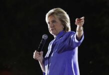 A woman speaking into a microphone while gesturing with her hand