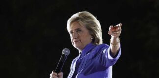 A woman speaking into a microphone while gesturing with her hand