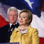 CLINTON’S Subpoena Standoff Explodes In Epstein Inquiry Hillary Clinton delivering a speech with Bill Clinton in the background