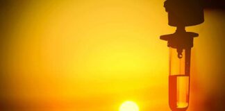 Silhouette of an IV drip against a sunset background