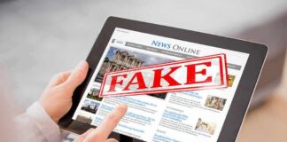 Person holding a tablet displaying a news website with a 'FAKE' stamp