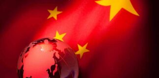 A globe illuminated against the backdrop of the Chinese flag