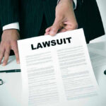 Federal Prosecutor Faces CHARGES For Stunning DEMAND Person holding a document titled LAWSUIT in office.