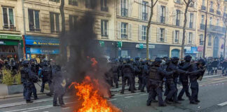 Protesters and police clash; fire in the street.
