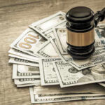 Gavel on a pile of hundred-dollar bills.