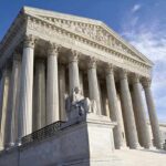 Exterior view of the Supreme Court building with columns and a statue of justice