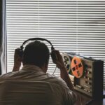 Person listening to music on headphones with a vintage tape recorder