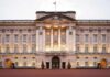 Front view of Buckingham Palace with illuminated facade and British flag