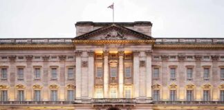 Front view of Buckingham Palace with illuminated facade and British flag